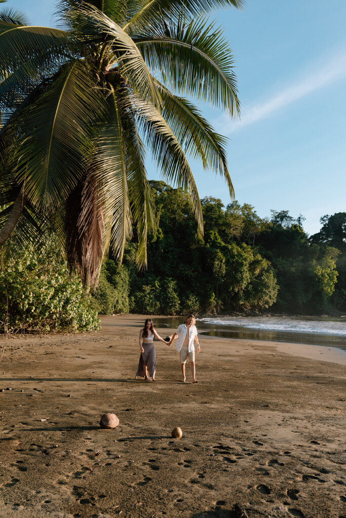 couple holding hands and walking on the beach in costa rica