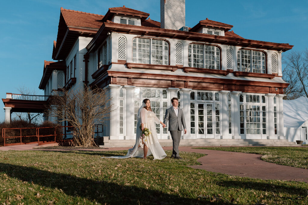 bride and groom walking in front of longview mansion for Missouri wedding