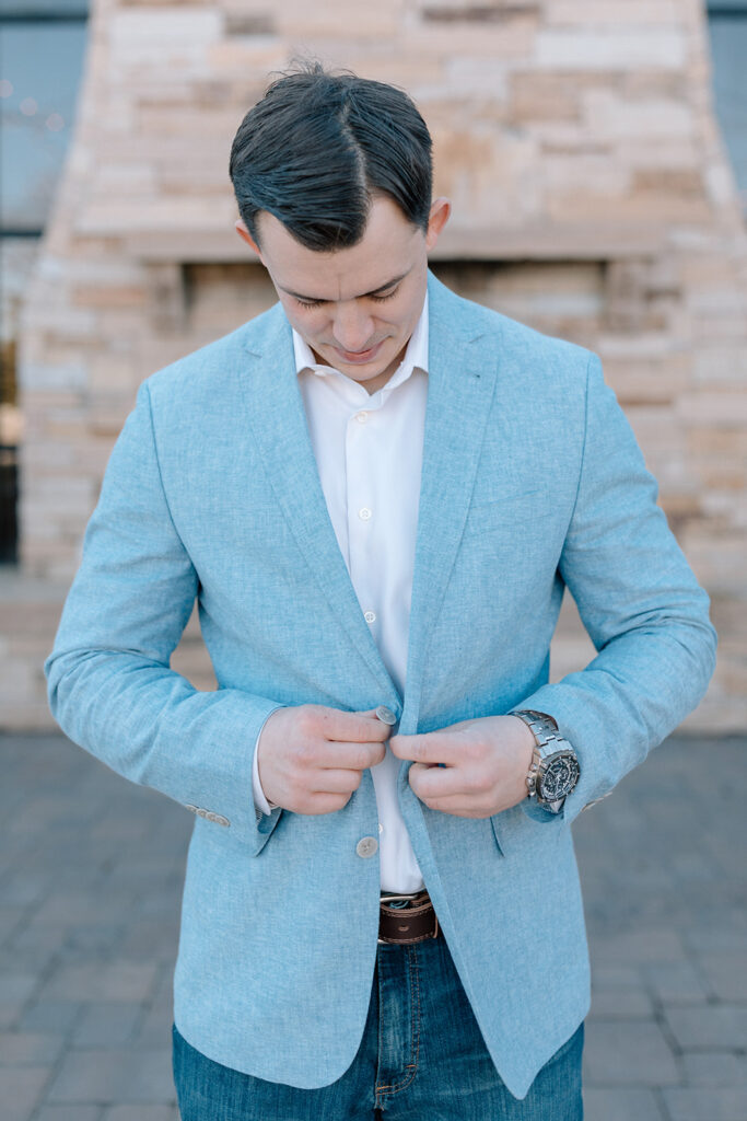 groom buttoning up suit jacket before ceremony