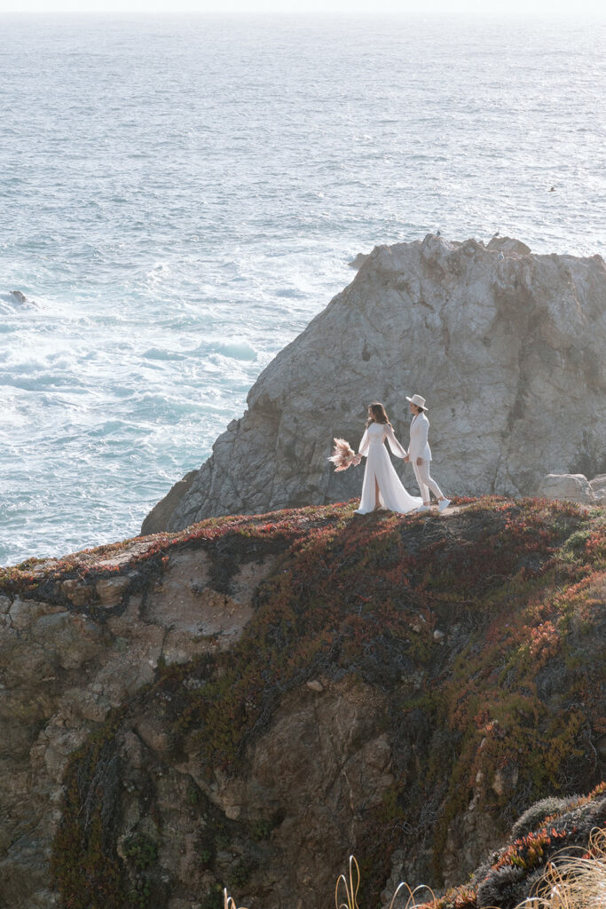 couple walking along cliffs in big sur