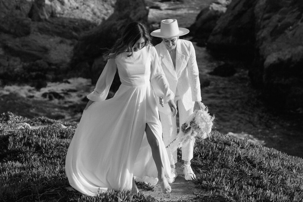 couple smiling romantic pose in front of california beach cliffs