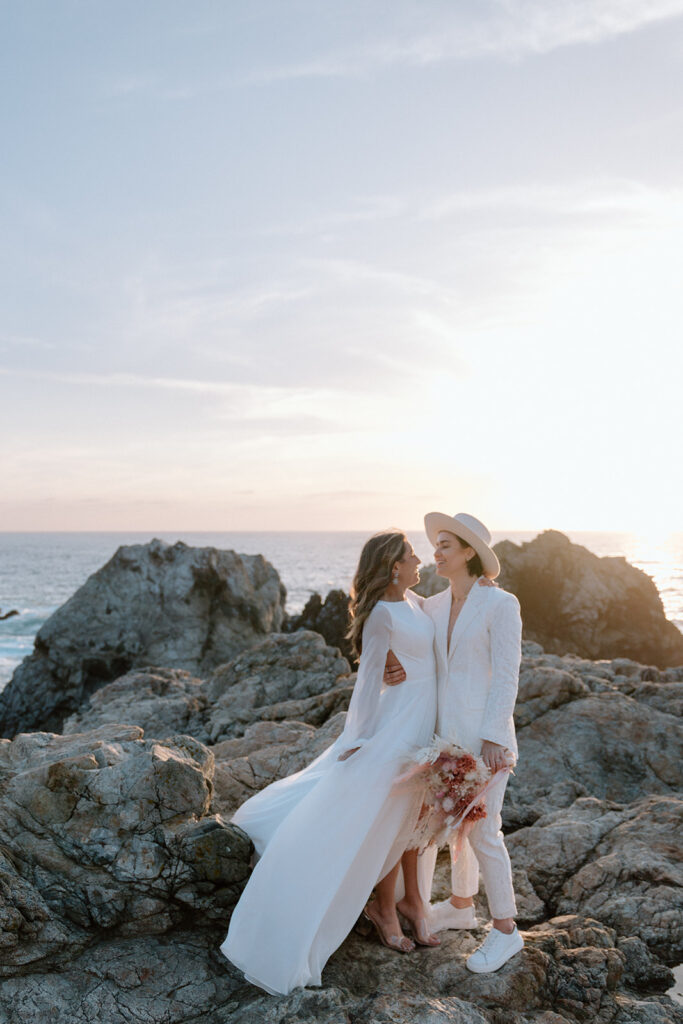 couple standing in front of beach sunset on the cliffs