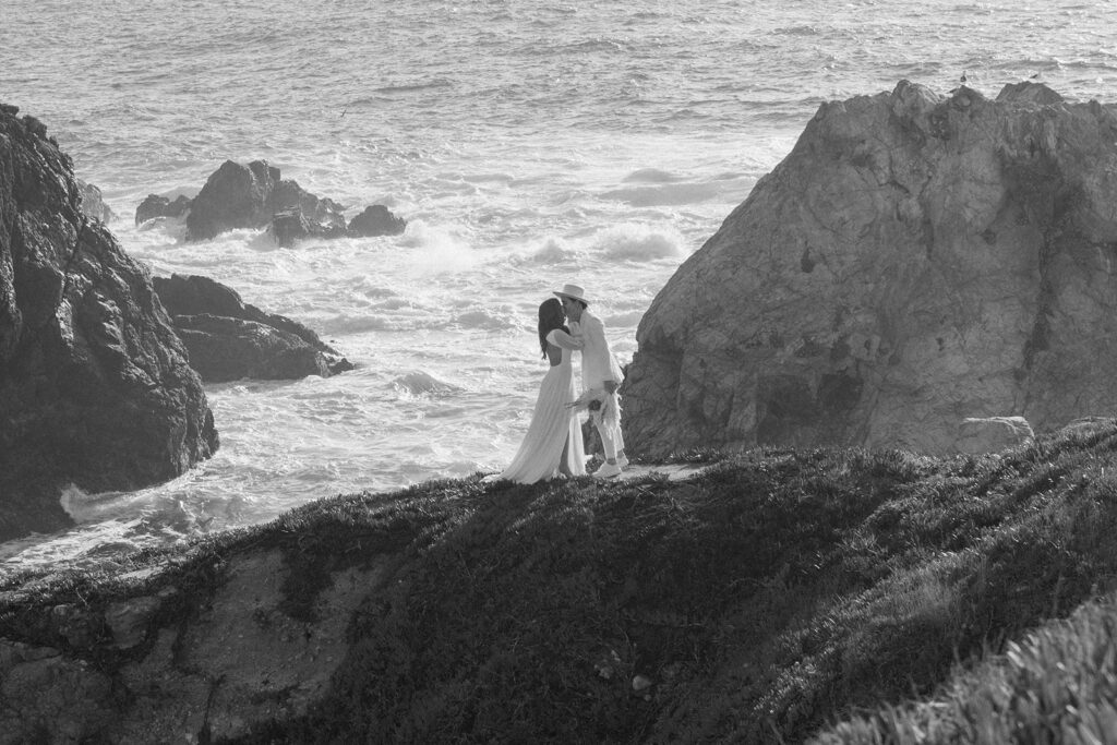 couple kissing with ocean in the background crashing waves