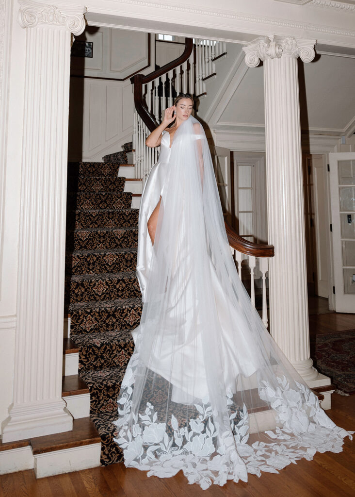 A model wears a Stephanie's Bridal Boutique wedding gown with a cathedral length veil while she poses for a styled wedding at the Historic Longview Mansion.