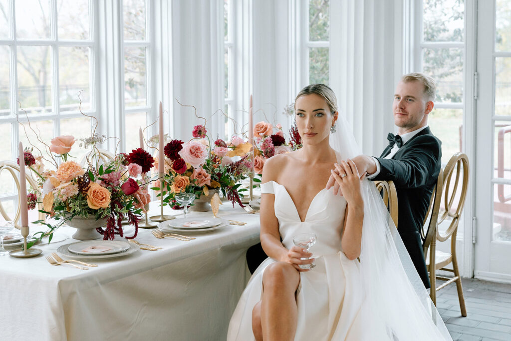 The model couple in an editorial wedding picture sitting at the table designed for the reception at Longview Mansion, a Kansas City luxury wedding venue.