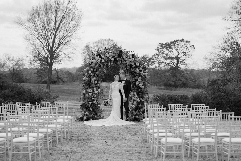 A styled wedding at Longview mansion featuring a ceremony in the Historic Sunken Garden with ceremony chairs from Quest Events and a fall floral arch from Floriography KC.