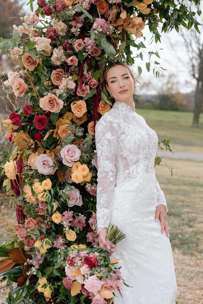 The bride poses for her bridal portraits at Longview Mansion with fall inspired florals and Stephanie's Bridal Boutique dress.