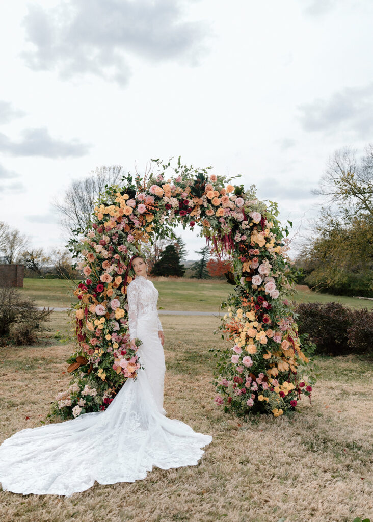 The bride stands under the luxury floral arch for wedding photos at the Historic Longview Mansion.