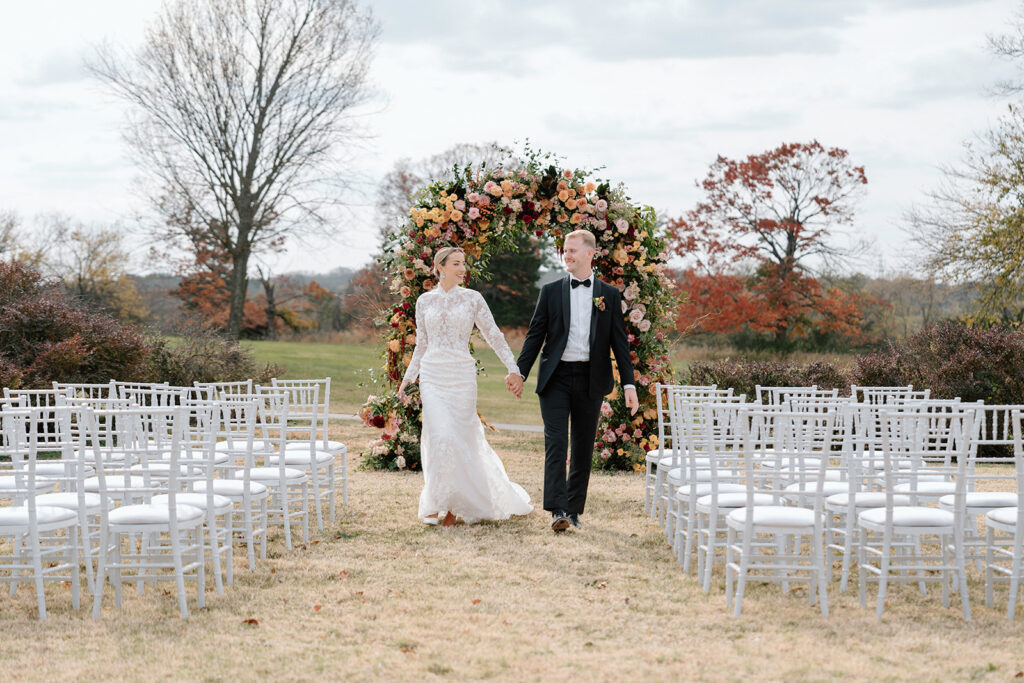 Taylor and Reece walk down the wedding aisle of a styled ceremony in the Historic Sunken Garden at the Longview Mansion wedding venue.