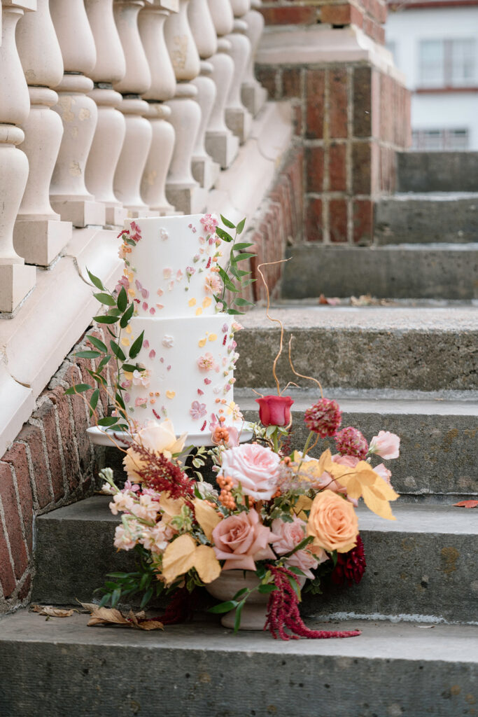 The cake from Kate Smith Soiree and the bouquet from Floriography KC decorating the steps in the Historic Sunken Garden ceremony at Longview Mansion.